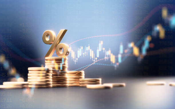 Percentage sign on top of coin stacks before blue financial graph. Horizontal composition with copy space. Business and finance concept.